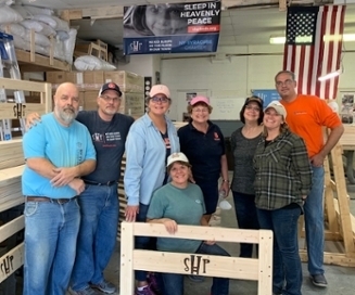ITS staff volunteers pose with a bed