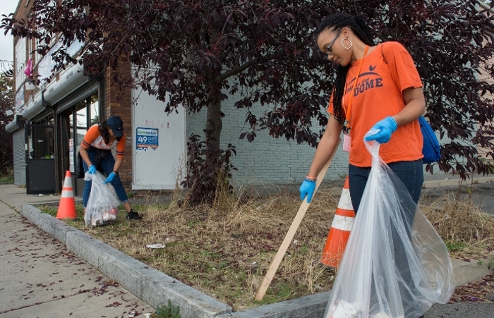 Student cleaning up a sidewalk